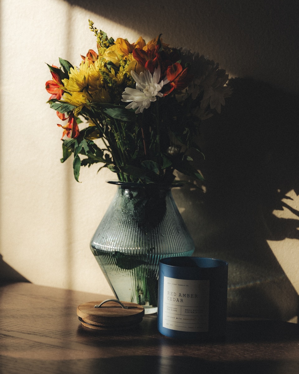 A vase of flowers sitting on a table next to a candle